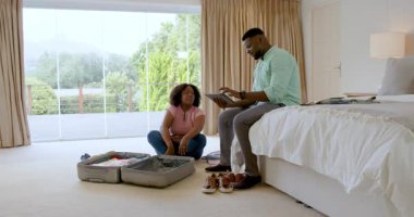 Afro-Amerikalı çift bavullarını yatak odasına topluyor, birlikte tatile hazırlanıyorlar. Seyahat, ilişki, tatil, giysi, beklenti, yolculuk