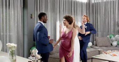 Mutlu gelin ve damat ve çeşitli arkadaşlar oturma odasında bir düğün resepsiyonunda dans ediyorlar. Kutlama, düğün, ilişki, parti ve arkadaşlık kavramı.