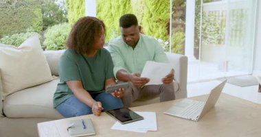 Afro-Amerikalı çift evde dizüstü bilgisayar ve tablet kullanarak mali konuları tartışıyor. planlama, bütçe, teknoloji, işbirliği, takım çalışması, yaşam tarzı