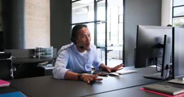 Kulaklıkla bilgisayar kullanan, işten bahseden ve ofiste kutlama yapan mutlu meslektaşlar. Takım çalışması, iş, kutlama ve iletişim konsepti.