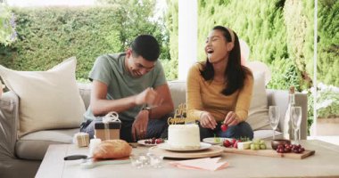 Genç çift doğum günü pastasının tadını çıkarıyor ve açık verandada birlikte gülüyorlar. Kutlama, aşk, mutluluk, açık hava, tatlı, parti