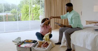 Afro-Amerikalı çift bavullarını yatak odasına topluyor, tatil gezisine hazırlanıyorlar. Seyahat, bagaj, hazırlık, turizm