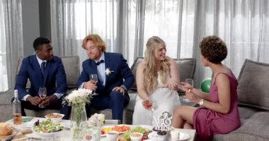 Mutlu gelin, damat ve arkadaşları oturma odasındaki düğün resepsiyonunda kadeh kaldırıyor. Kutlama, düğün, ilişki, parti ve arkadaşlık kavramı.