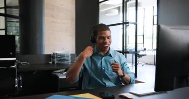 Kulaklıkla bilgisayar kullanan, işten bahseden ve ofiste kutlama yapan mutlu meslektaşlar. Takım çalışması, iş, kutlama ve iletişim konsepti.