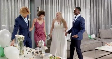 Mutlu gelin ve damat ve çeşitli arkadaşlar oturma odasında bir düğün resepsiyonunda dans ediyorlar. Kutlama, düğün, ilişki, parti ve arkadaşlık kavramı.