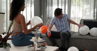 Mutlu çift balonları şişiriyor ve oturma odasında doğum günü partisine hazırlanıyor. Kutlama, hazırlık, doğum günü, ilişki, parti ve yaşam tarzı konsepti.