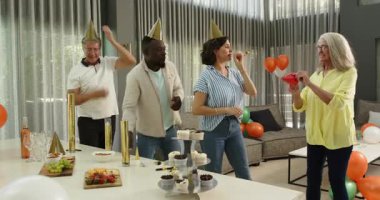 Ofis salonunda parti trompetleri kullanarak birlikte kutlama yapan çeşitli meslektaşlarınız kutlu olsun. Kutlama, eğlence, birliktelik, ofis partisi ve iş konsepti.