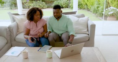Afro-Amerikalı çift evde mali konuları tartışıyor, tablet kullanıyor ve not tutuyorlar. Bütçe, planlama, teknoloji, yaşam tarzı