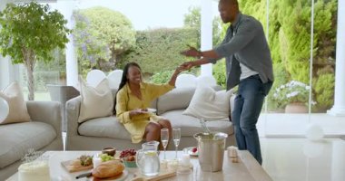 Afro-Amerikalı çift, kutlama masaları kurarak evde sevinçle kucaklaşıyorlar. Kutlama, mutluluk, birliktelik, yemek, yaşam tarzı, aşk