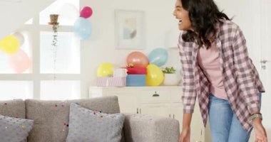 Gri kanepeye yaslanan bir kadın oturma odasında faraş topluyor, konfeti, fırça ve fotokopi uzayı ile. Temizlik, sonuç, kutlama, gündelik, canlı, pastel, ev