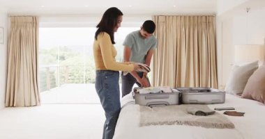 Genç çift yataklarına bavullarını topluyor, evde birlikte tatile hazırlanıyorlar. Seyahat, bagaj, macera, planlama, yaşam tarzı, hazırlık