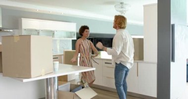 Mutlu ve çift birlikte dans ediyor ve mutfak tezgahında kutularla kucaklaşıyorlar. Taşınmak, konut ve ev hayatı kavramı.