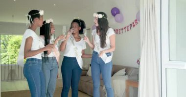 Çeşitli bayan arkadaşlar gelini kutlamak için flüt tokuşturuyor ve oturma odasında kadeh tokuşturup sarılıyorlar. Kutlama, arkadaşlık, neşe, stil, sosyal, ailevi, şenlikli