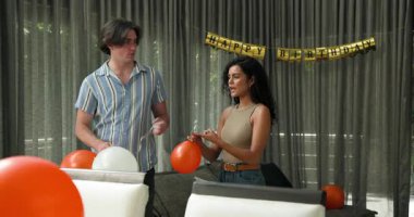 Mutlu çift balonları şişiriyor ve oturma odasında doğum günü partisine hazırlanıyor. Kutlama, hazırlık, doğum günü, ilişki, parti ve yaşam tarzı konsepti.