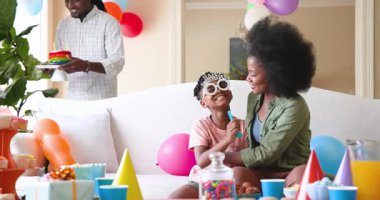 Mutlu siyah çift ve onların çok ırklı oğulları çocuğun doğum gününü kutluyor, çocuk evde pastadan mum üflüyor. Doğum günü, kutlama, parti, aile, çocukluk, ev hayatı ve ilişki kavramı.