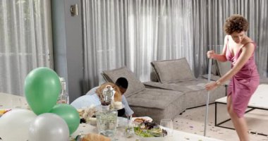 Mutlu damat ve farklı arkadaşlar oturma odasındaki düğün töreninden sonra temizlik yapıyorlar. Kutlama, düğün, ilişki, parti ve arkadaşlık kavramı.