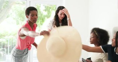 Çeşitli bayan arkadaşlar evde cam kenarında stil yapmaya, güneş şapkasıyla poz vermeye, sonra da kot pantolon sınıflandırmaya başladılar. Yaşam tarzı, günlük, moda, arkadaşlık, açık hava, canlı, neşeli