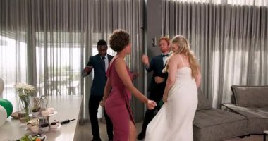 Mutlu gelin ve damat ve çeşitli arkadaşlar oturma odasında bir düğün resepsiyonunda dans ediyorlar. Kutlama, düğün, ilişki, parti ve arkadaşlık kavramı.