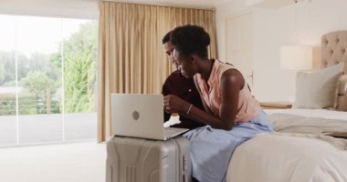 Genç çift rahat yatak odasında dizüstü bilgisayar kullanıyor, seyahat macerası planlıyorlar. teknoloji, tatil, yaşam tarzı, gezinme