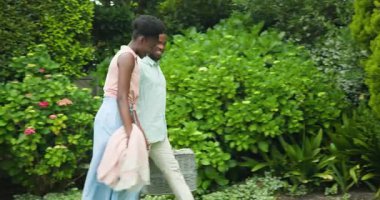 Genç çift çimlerin üzerinde piknik yapıyor, gülüyor ve dışarıda eğleniyor. Rahatlama, kahkaha, eğlence, bağlanma, yaz, mutluluk