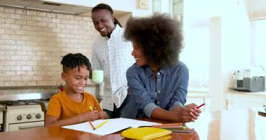 Mutlu siyahi ebeveynler ve yemek masasında ödev yapan çok ırklı oğulları, evde oğullarına yardım eden ebeveynler. Eğitim, okul, aile, çocukluk, ev hayatı ve ilişki kavramı.