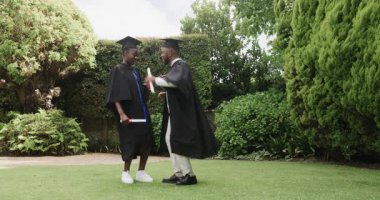 Mezuniyeti bahçede kutluyorlar, mezunlar kep ve cübbe giyiyorlar, neşeli hissediyorlar. Kutlama, başarı, tören, başarı, açık hava, gelenekler