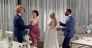 Mutlu gelin ve damat ve çeşitli arkadaşlar oturma odasındaki düğün resepsiyonunda konfeti atıyorlar. Kutlama, düğün, ilişki, parti ve arkadaşlık kavramı.