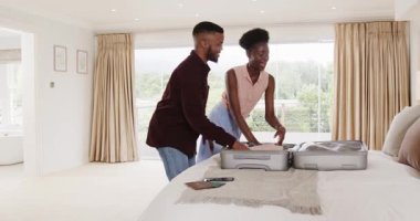 Afro-Amerikalı çift bavullarını toplayıp seyahat macerasına hazırlanıyorlar. tatil, bagaj, hazırlık, yolculuk