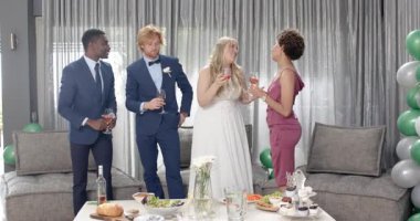 Mutlu gelin, damat ve arkadaşları oturma odasındaki düğün resepsiyonunda kadeh kaldırıyor. Kutlama, düğün, ilişki, parti ve arkadaşlık kavramı.