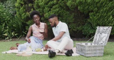 Genç çift pikniği seviyor, güneşli bir parkta yemek ve kahkaha paylaşıyorlar. Açık hava, rahatlama, bağlanma, yaz tatili, mutluluk, boş zaman