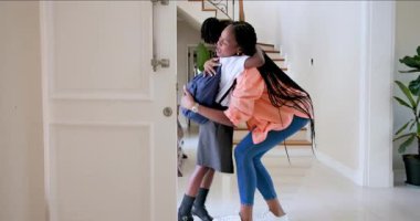 Mutlu siyah anne, okuldaki gününden dönen kız öğrencisini evinin kapısında karşılıyor. Aile, çocukluk, ev hayatı ve ilişki kavramı.