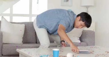 Adam oturma odasını süpürgeyle temizlerken başka biri de partiden sonra ortalığı topluyor. Oda servisi, ev işleri, ev işleri, süpürme, ev temizliği, bakım