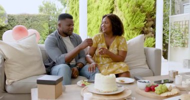 Pasta ve şampanyayla kutlayan Afro-Amerikan çift terasta birlikte. Kutlama, neşe, keyif, romantizm, yaşam tarzı