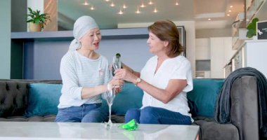 Mutlu kıdemli çeşitli bayan arkadaşlar oturma odasında şampanya içip kutlama yapıyorlar. Kutlama, kanser farkındalığı, parti, yaşlılar yaşam tarzı ve arkadaşlık kavramı.