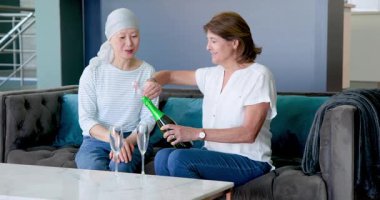 Mutlu kıdemli çeşitli bayan arkadaşlar oturma odasında şampanya içip kutlama yapıyorlar. Kutlama, kanser farkındalığı, parti, yaşlılar yaşam tarzı ve arkadaşlık kavramı.