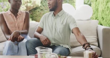 Kanepede hediyeleşen genç bir çift, birlikte gülüp eğleniyorlar. Hediye değişimi, kutlama, mutluluk, bağlılık, şenlik, birliktelik