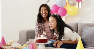 Çeşitli bayan arkadaşlar 18. doğum gününü evde pasta, aperatif ve balonlarla kutluyorlar. Kilometre taşı, şenlikli, neşeli, pastel, konfeti, iç mekan, kanepe