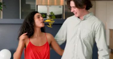 Konfeti atan ve oturma odasındaki yıldönümü partisinde kutlama yapan mutlu çift. Kutlama, yıldönümü, ilişki, parti ve yaşam tarzı konsepti.