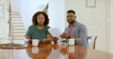 Afro-Amerikalı çift, ellerinde tablet ve kahve kupalarıyla belgeleri inceliyor. Finans, ev ofisi, teknoloji, çeşitlilik, işbirliği, yaşam tarzı