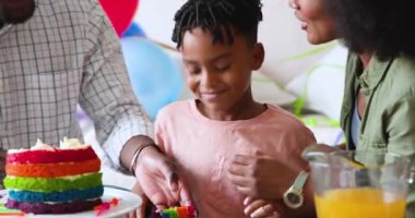 Mutlu siyah çift ve çok ırklı oğulları doğum günü pastasını dilimliyor, çocuğun doğum gününü evde kutluyorlar. Doğum günü, kutlama, parti, aile, çocukluk, ev hayatı ve ilişki kavramı.