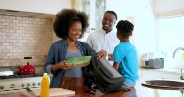 Mutlu siyah çift ve onların çok ırklı oğlu evde okula gitmek için mutfakta yemek hazırlıyorlar. Eğitim, okul, aile, çocukluk, ev hayatı ve ilişki kavramı.