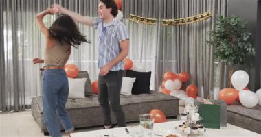 Birlikte dans eden ve oturma odasındaki bir doğum günü partisinde kutlama yapan mutlu çift. Kutlama, doğum günü, ilişki, parti ve yaşam tarzı konsepti.