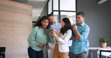 Tablet kullanan, iş tartışan ve ofiste kutlama yapan mutlu meslektaşlar. Takım çalışması, iş, kutlama ve iletişim konsepti.