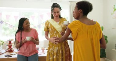 Çeşitli bayan arkadaşlar ellerinde çay fincanları, duş masasında bebek çarpması ve telefon özçekimleri tutuyorlar. Kutlama, arkadaşlık, annelik, neşe, neşe, samimiyet, dekor