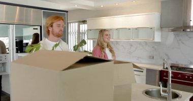 Mutlu çift ev turu yapıyor, mutfakta yürüyor, içeriden bahsediyor, gülümsüyor. Taşınmak, konut ve ev hayatı kavramı.