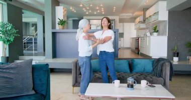 Kanepede oturan, kucaklaşan ve salonda konuşan kıdemli çeşitli bayan arkadaşlar. Kutlama, kanser farkındalığı, parti, yaşlılar yaşam tarzı ve arkadaşlık kavramı.