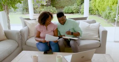 Mutlu çift başarıyı gazeteler uçarken kutluyor, evdeki kanepede oturuyor. Kutlama, başarı, zafer, mutluluk, yaşam tarzı, yurtiçi