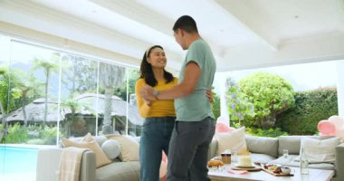 Oturma odasında balonlar ve pastayla neşeyle dans eden genç bir çift. Kutlama, mutluluk, ev, yaşam tarzı, şenlik