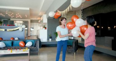 Mutlu kıdemli çeşitli bayan arkadaşlar oturma odasında doğum günü partisi için dekorasyon hazırlıyorlar. Kutlama, hazırlık, doğum günü, parti, yaşlılar yaşam tarzı ve arkadaşlık kavramı.