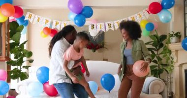 Mutlu siyah çift ve onların çok ırklı oğulları kucaklaşıp gülümsüyor, evde oğlanın doğum gününü kutluyorlar. Doğum günü, kutlama, parti, aile, çocukluk, ev hayatı ve ilişki kavramı.